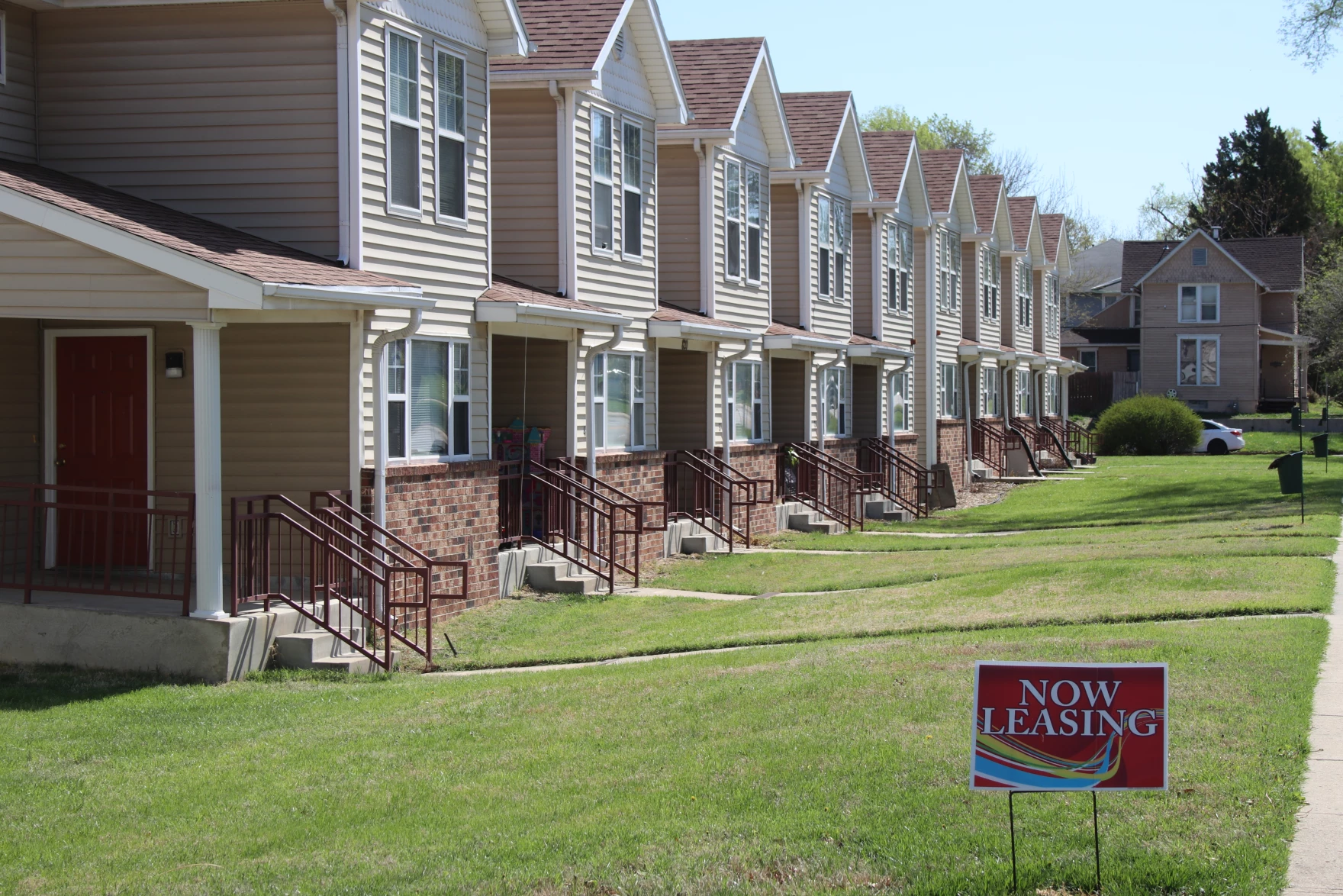 Row of houses with a "Now Leasing" sign in the yard
