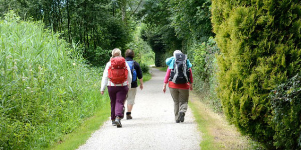 Image of ladies with hiking gear walking down a rural, woodsy lane.