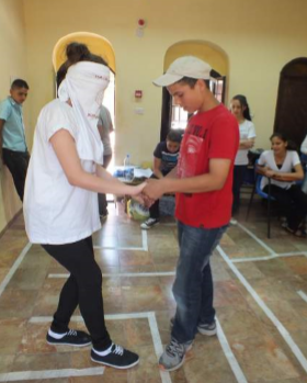 Photo of a blindfolded woman and a boy doing an exercise in front of others.