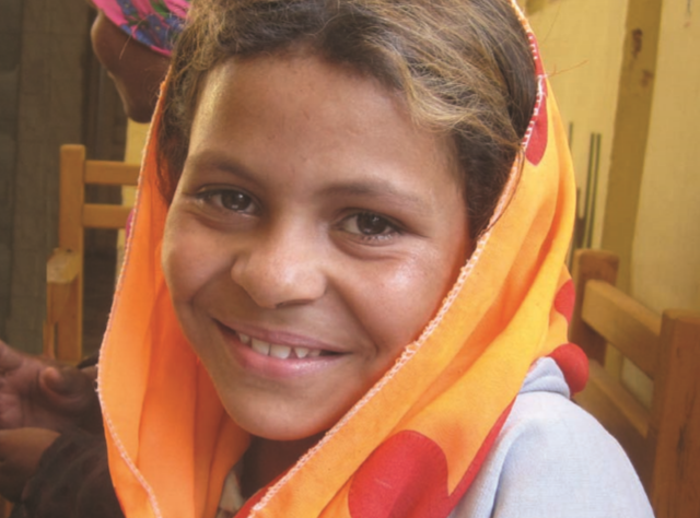 Image of smiling girl with colorful head scarf.
