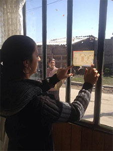 Photo of Roma Mother places Immunization Schedule Sticker on the Window at her House