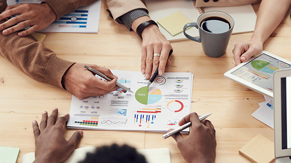 Image of a group of multiracial hands working together on a chart.