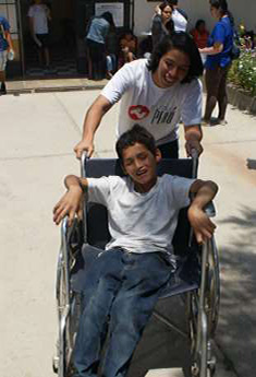 Photo of Gabriel Torres, Nutre Perú volunteer, having fun with Richard a child with cerebral palsy from Catahuasi.