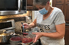 Woman cooking in her kitchen wearing a mask.