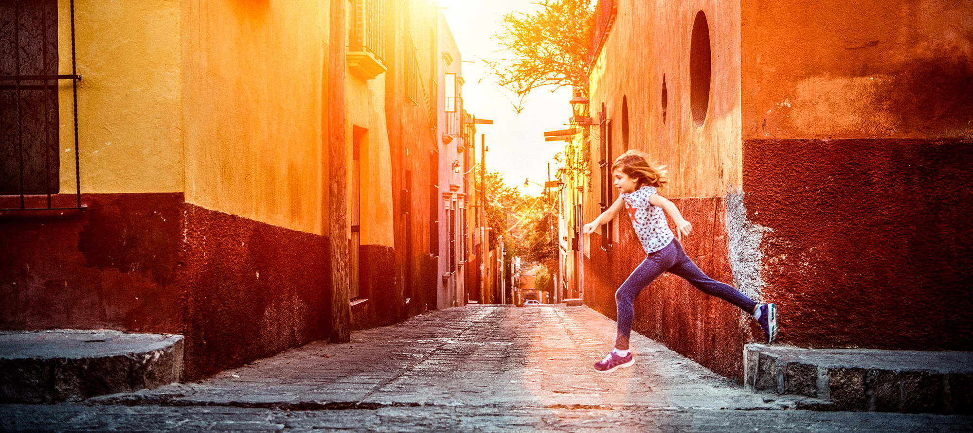  Young girl leaping across a street in Mexico.