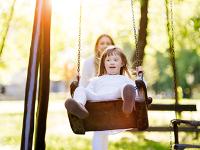 Photo of a disabled girl in a park on a swing.