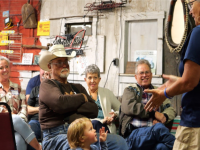 A group of people sit at a meeting. The clothing and atmosphere is rural casual.